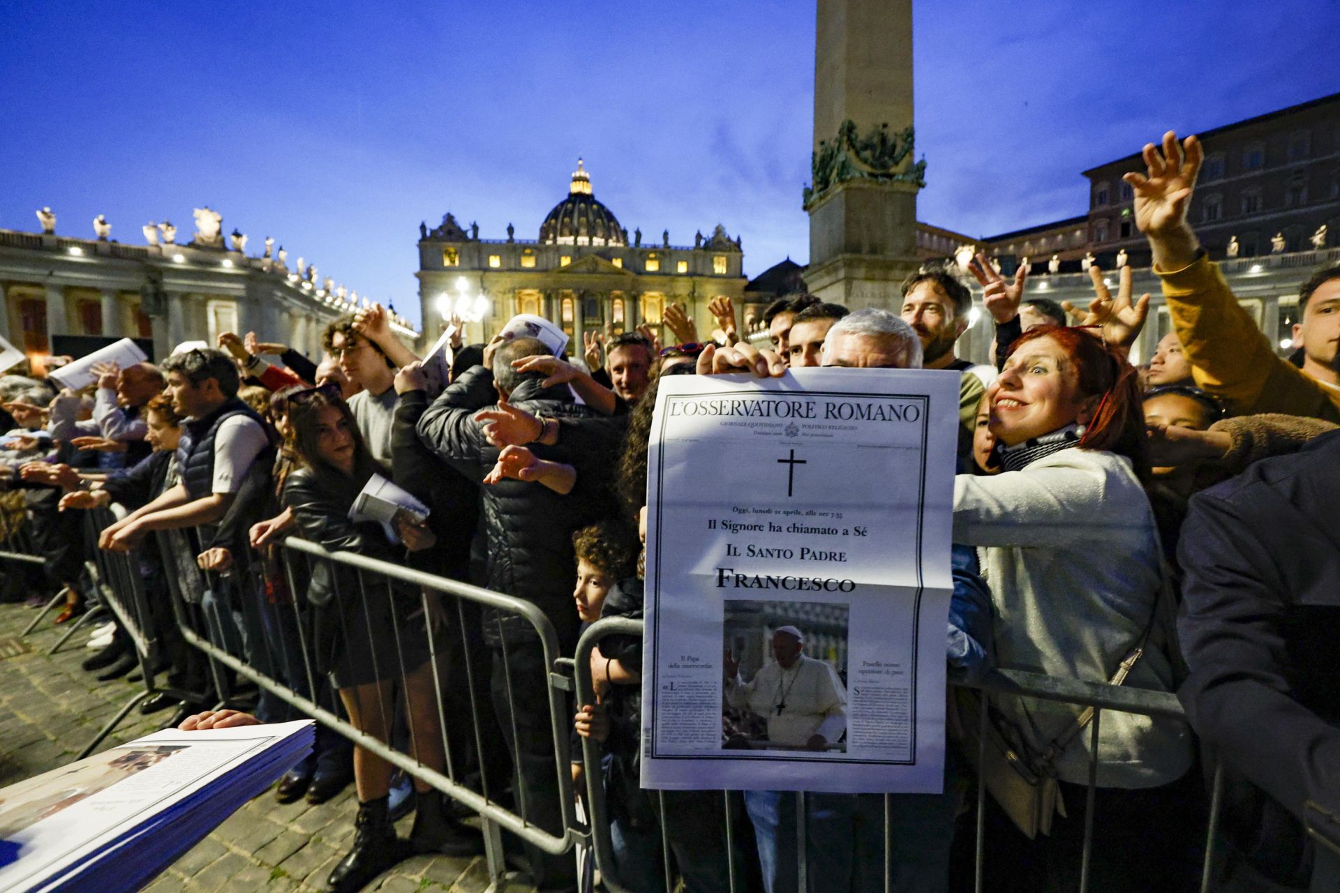 Varias personas toman un ejemplar de la edición especial del diario vaticano L'Osservatore Romano que anuncia la muerte del Papa.